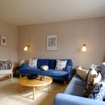 Wohnzimmer mit blauem Sofa, runden Tisch und Wandbildern