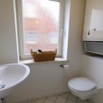Badezimmer mit Waschbecken, Toilette und Fenster mit Korb.