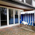Blau-weiße Strandkorb mit Nummer 5067 vor Haus mit Fenstern und Ziegelmauer.