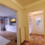 Haus mit Wohnbereich, TV und Terrasse. Tür führt zum Flur mit Regal.