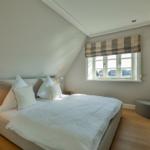 Schlafzimmer mit Dachschrägen, Bett, Fenster und Fernseher