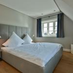 Schlafzimmer mit Bett, Fenster, TV und Nachttisch.