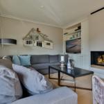 Wohnzimmer mit Sofa, Kamin und Fernseher an der Wand.