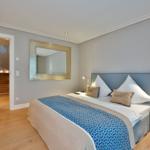Schlafzimmer mit Bett, Spiegel und Nachttisch. Tür führt zu Treppe.