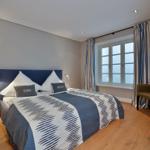 Schlafzimmer mit Bett, Fenster und Stuhl.