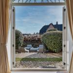 Durch die offene Tür blickt man auf eine Terrasse mit Sitzmöbeln und einen gepflasterten Weg.