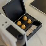 Coffee machine with four capsules and sugar packets on countertop