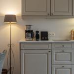 Kitchen area with light cabinets, coffee machine, and wall sockets.