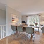 Dining area with table and chairs, living area with sofa and garden view