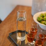 On a wooden table, a water carafe and three glasses with rosé wine.
