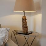 Table lamp with wooden base on a metal table next to a sofa.