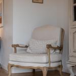 Antique chair with cushion in living area with wooden floor and wall picture.