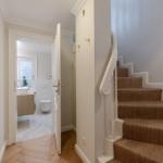 Staircase with carpeted steps and view into bathroom with bathtub and toilet.