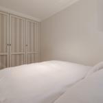 Bedroom with bed, wardrobe, and wall art featuring boats.