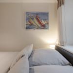 Bedroom with bed, wall painting, and window with curtain.