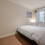 Bedroom with bed, window, and wall picture.