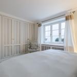 Bedroom with bed, wardrobe, and window with curtains.