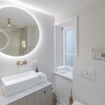 Bathroom with round mirror, sink, and window