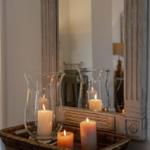 A basket with lit candles sits in front of a mirror with a wooden frame.