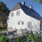 White house with dark roof, garden area, and seating.