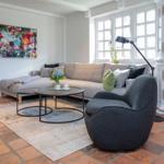 A living room with sofa, armchair, table, and wall art.