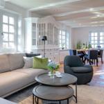 Living and dining area with sofa, chairs, and wooden floor.