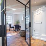 Bright kitchen with dining area and white wardrobe. Terracotta floor and glass walls.