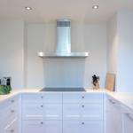 Modern kitchen with white cabinets and stainless steel range hood.
