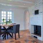 Dining room with table, chairs, and tiled fireplace on the wall.