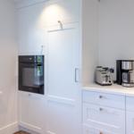 Kitchen with white cabinets, built-in oven, and countertop with coffee maker and toaster.