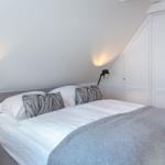 Bedroom with double bed, white walls, and white wardrobes.