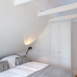 Bedroom with double bed, white wardrobes, and wooden beams on the ceiling.