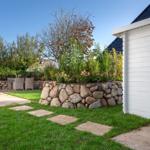 Backyard with stone wall, flower bed, and white wooden shed