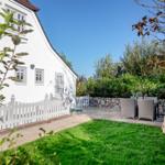White villa with garden, terrace, and garden furniture.