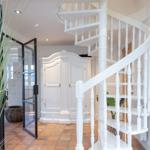 White spiral staircase, large wardrobe and terracotta floor in entrance area