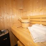Sauna mit Holzbank, gefalteten Handtüchern und Holzwaschkanister.