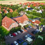 Großes Haus mit rotem Dach und Parkplatz in grüner Umgebung