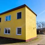 Seitenansicht der Unterkunft mit Zugangsbereich und Stellplatz