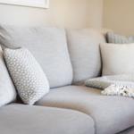 A gray sofa with pillows and a blanket.