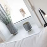 A windowsill with a plant, cup, and a lamp.