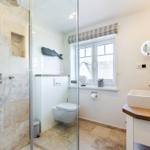 Bathroom with shower, toilet, and sink with wooden countertop.