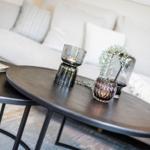 Round table with glass containers and book in front of sofa