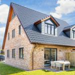 Two-story house with brick facade and dormer windows. Outdoor area with table and chairs.