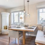 Dining room with wooden table, bench, and white windows.
