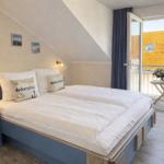 Schlafzimmer mit Dachschrägen, Bett mit Ankern, Nachttische und Balkonansicht.