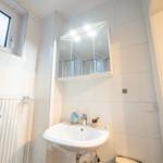 Badezimmer mit Waschbecken, Spiegelschrank und Fenster