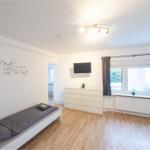 Schlafzimmer mit Bett, Schrank und Fenster. Wanddekoration und Holzboden.