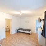Schlafzimmer mit Bett, Schreibtisch und TV. Durchgang zu Essbereich und Küche.