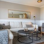 Wohnzimmer mit Sofa, Sessel und runden Tischen auf Teppich