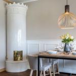 Esszimmer mit weißem Kachelofen, Holztisch und Lampe